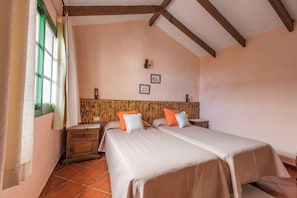 A bedroom with two beds, wooden headboard, tiled floor, and a window with curtains.