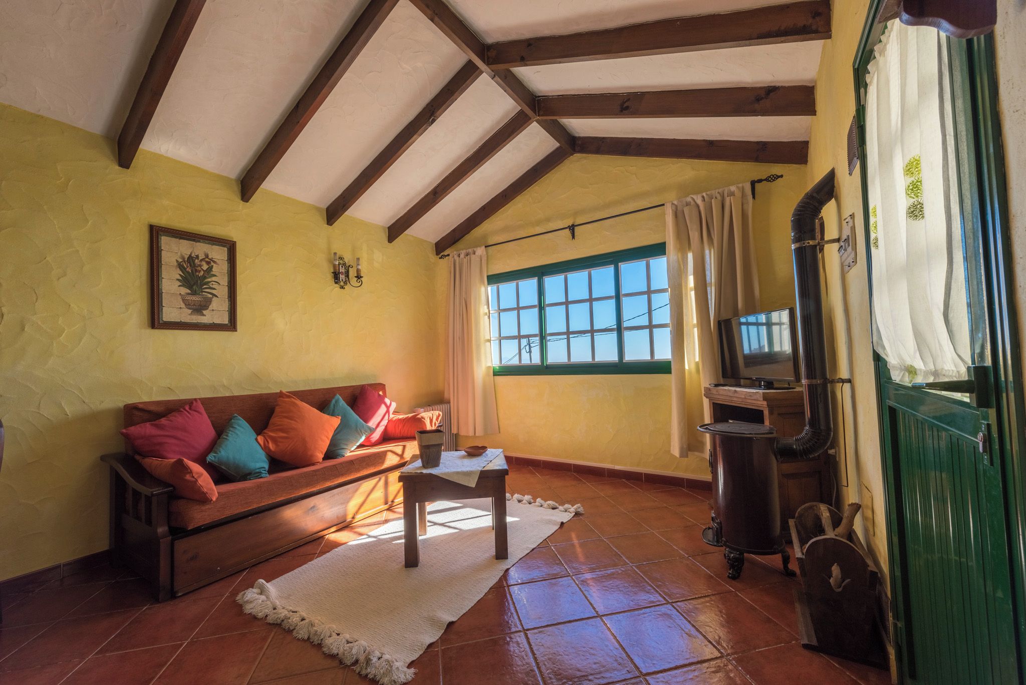 Una sala de estar acogedora con un sofá de madera, un televisor y una puerta verde.