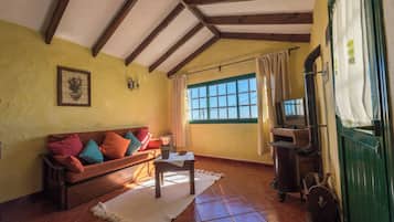 Una sala de estar acogedora con un sofá de madera, un televisor y una puerta verde.