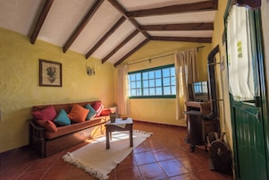 Una sala de estar acogedora con un sofá de madera, un televisor y una puerta verde.