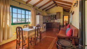 A cozy living room with a dining area, a sofa, and a fireplace. - Casas Rurales Herreñas (Valverde)