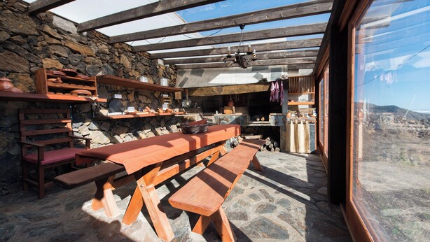 A rustic outdoor dining area with wooden benches and stone walls. - Casas Rurales Herreñas (Valverde)
