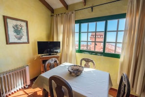 Un comedor con mesa, sillas, televisor y ventana con vistas.