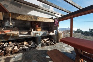 Una cocina rústica con encimera de piedra, vigas de madera y vistas amplias a través de un ventanal.