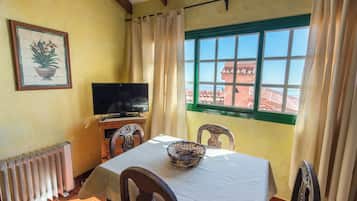 Un comedor con mesa, sillas, televisor y ventana con vistas.