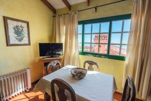 A dining area with a table, chairs, a television, and a window with a view.