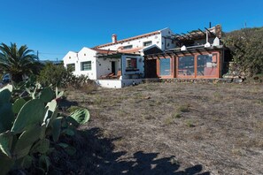 A two-story house with a patio area, a stone wall, and a cactus plant. - Casas Rurales Herreñas (Valverde)