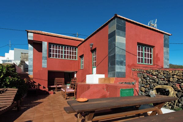A red building with a stone wall and a wooden bench in the foreground.