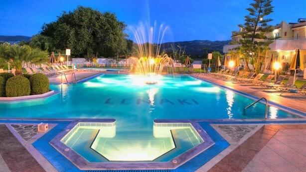 Una piscina con una fuente, sillas de descanso y una zona de hidromasaje.