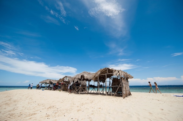 A beach with thatched-roof huts and a clear blue sky.