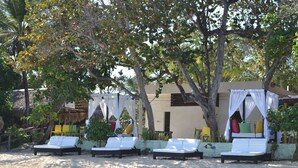 A beachside lounge area with white cushioned chairs and a canopy structure. - Paradise Island Beach Resort (Punta Rucia)