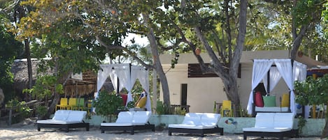 A beachside lounge area with white cushioned chairs and a canopy structure.