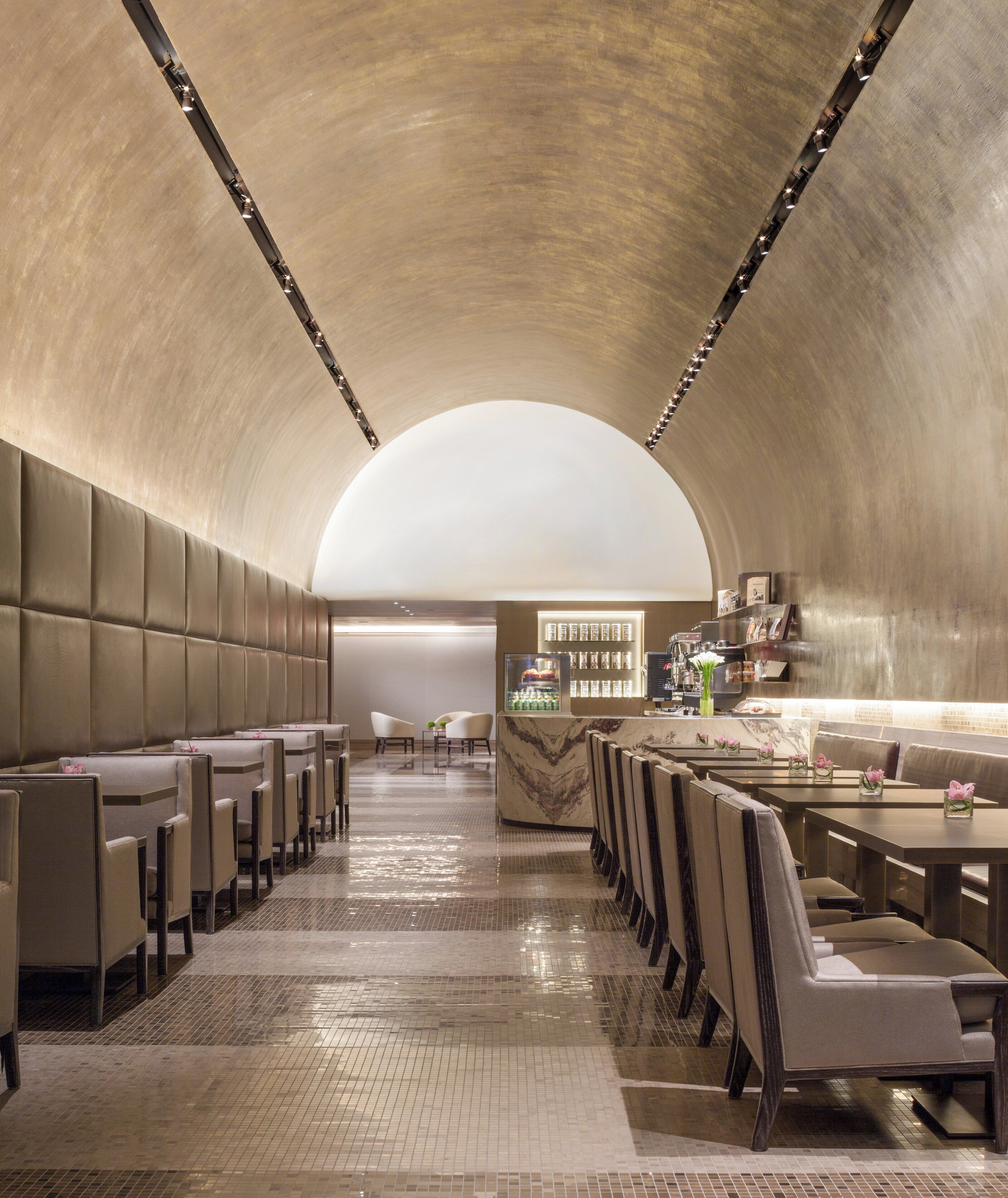 A modern restaurant with a curved ceiling, rows of booths, and a bar area.