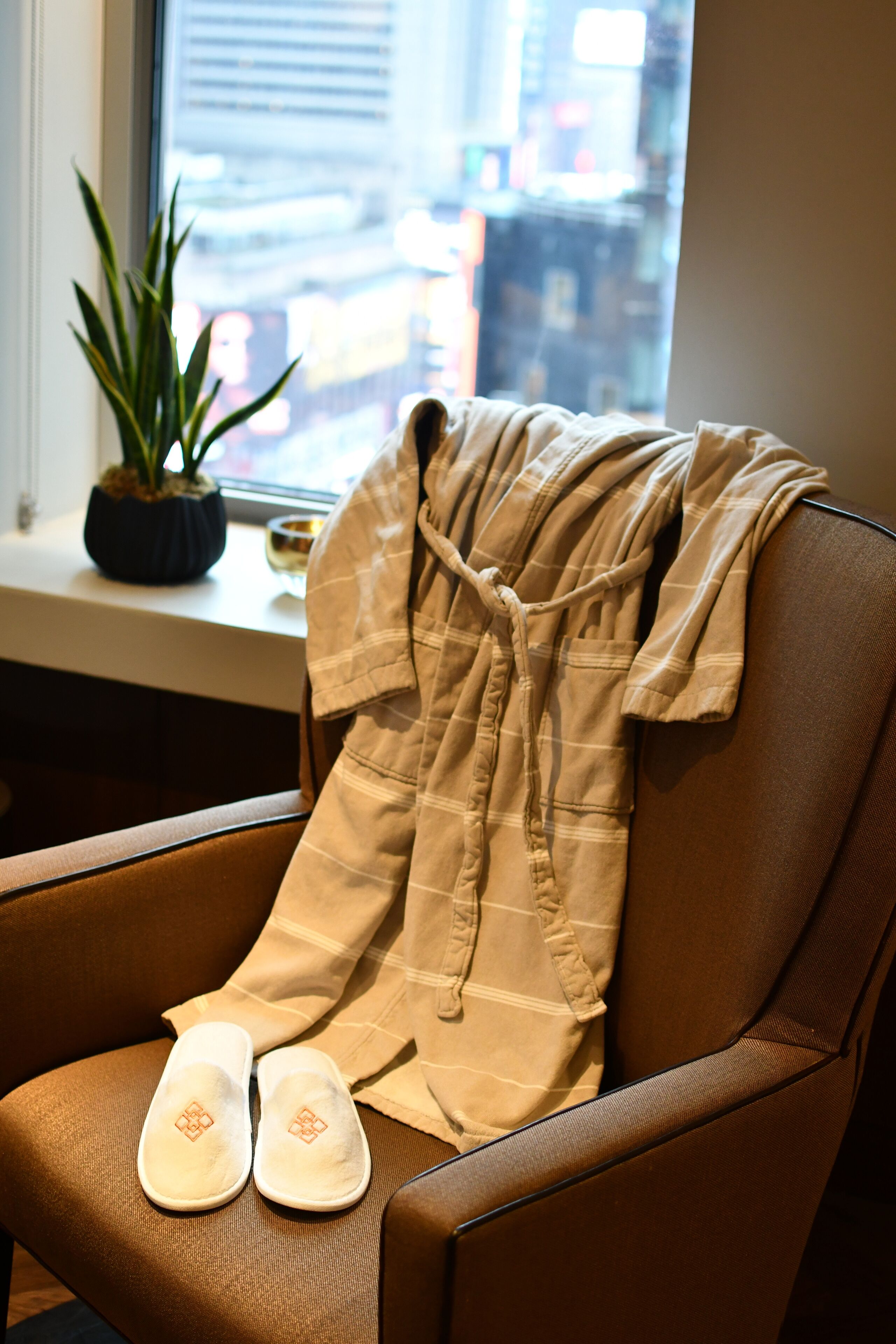 A chair with a pair of slippers and a robe draped over it.