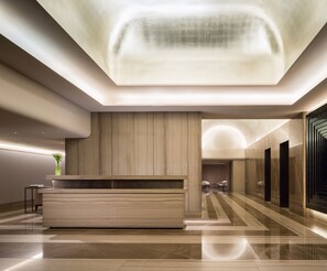 A modern lobby with a reception desk, seating area, and a large, illuminated ceiling feature.
