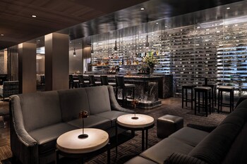 A modern hotel room with a large bed, a desk, a chair, a TV, and a window with curtains. at The Knickerbocker Hotel