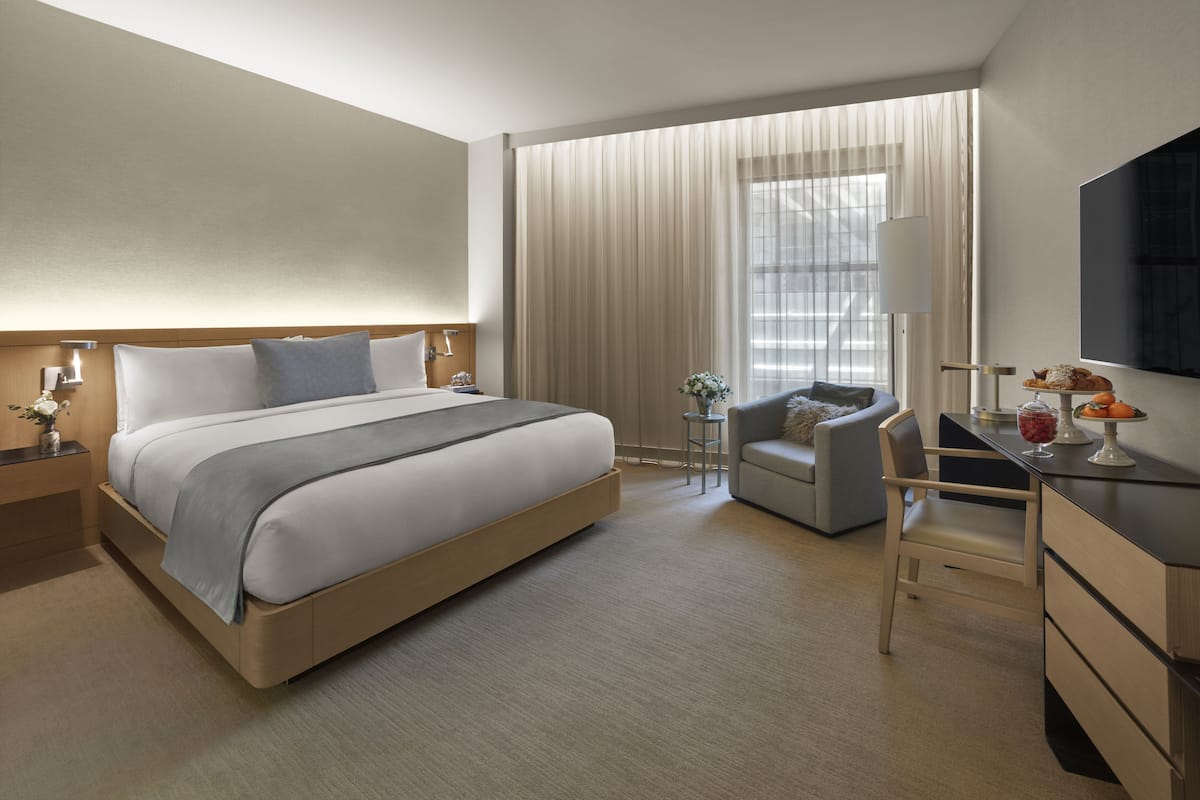 Una habitación de hotel moderna con una cama grande, un escritorio, una silla y un televisor.
