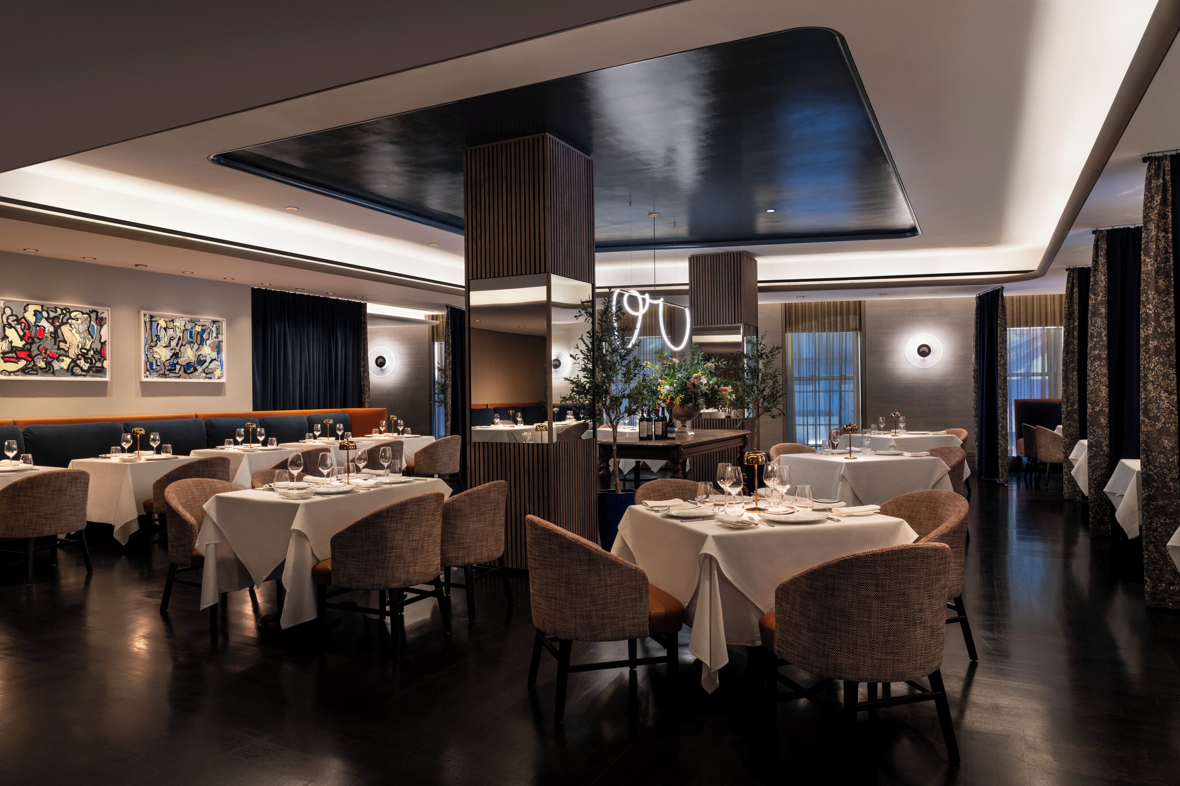 A modern restaurant with multiple dining tables and booths, featuring contemporary decor and ambient lighting.