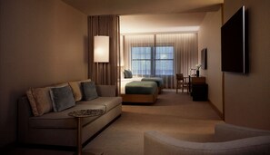 A hotel room with a sofa, a bed, a desk, and a TV.