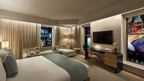 A modern hotel room with a large bed, a desk, a chair, a TV, and a window with curtains.