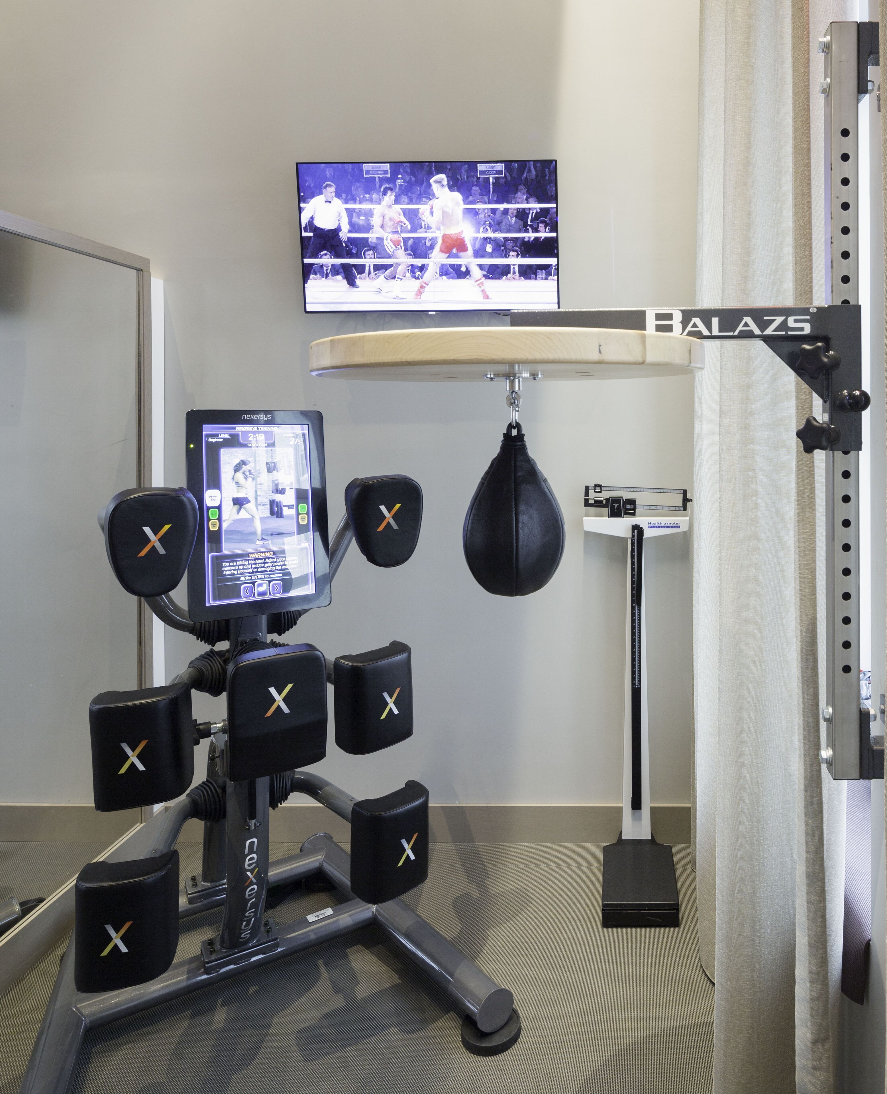 A boxing training area with a punching bag, a digital monitor, and a weight scale.