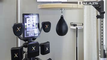 A boxing training area with a punching bag, a digital monitor, and a weight scale.