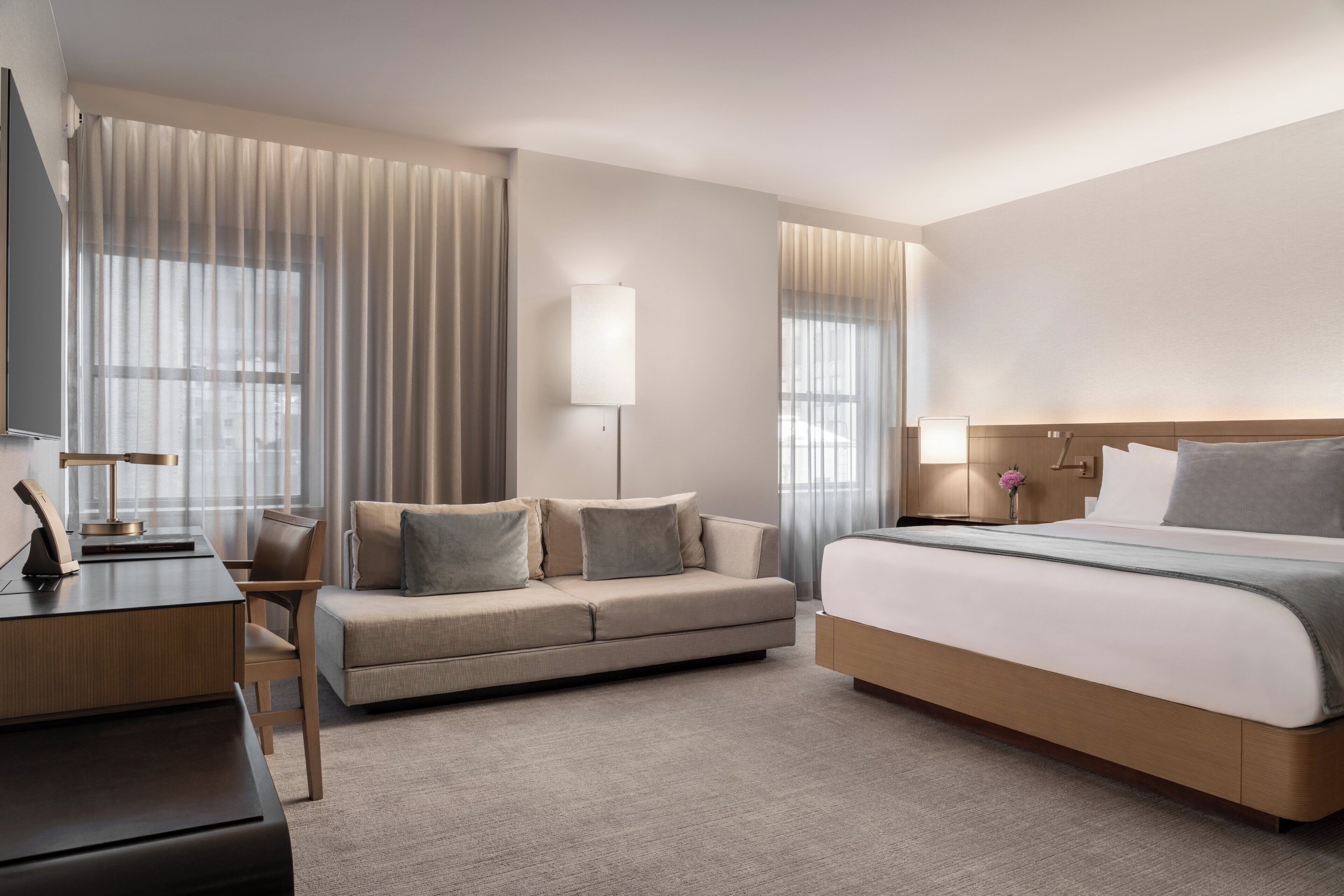 Une chambre d’hôtel moderne équipée d’un grand lit, d’un canapé, d’un bureau et d’une télévision.