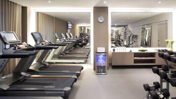 A gym with treadmills, a water dispenser, and a clock on the wall.