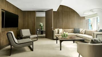 A modern living room with a sofa, armchairs, a coffee table, and a flat-screen TV mounted on the wall.