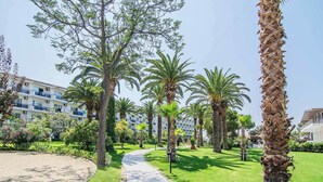 Un sendero bordeado de palmeras que conduce a un edificio con balcones.