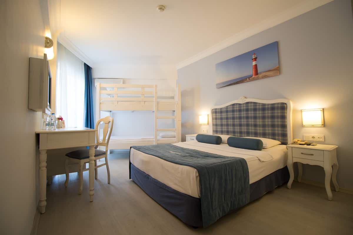 Une chambre avec un lit superposé, un bureau et une chaise. Un tableau représentant un phare est accroché au mur.
