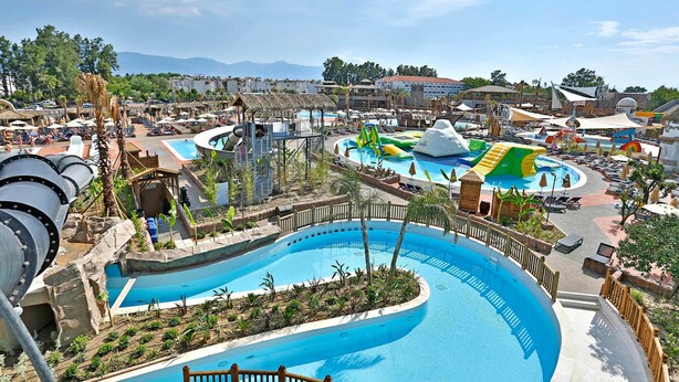 Un resort con una piscina grande, toboganes acuáticos y diversas actividades recreativas.