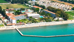 Vista aérea de un complejo turístico costero con playa, piscina y varios edificios.