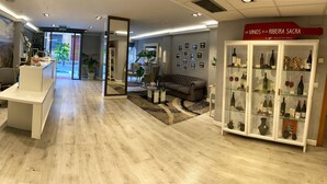 A modern interior with a reception desk, a seating area with a sofa, and a wine display. - Hotel Ribeira Sacra (Monforte de Lemos)