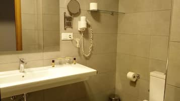 Un bagno con un lavandino bianco, uno specchio, un WC, un cestino e un portascopino.