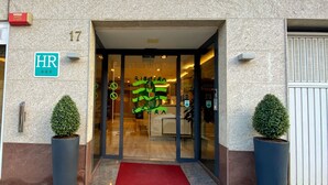 A hotel entrance with a glass door, a red carpet, and two potted plants. - Hotel Ribeira Sacra (Monforte de Lemos)