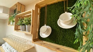 A room with a wooden shelf holding potted plants and a wall-mounted rack with white cups and saucers. - Hotel Ribeira Sacra (Monforte de Lemos)