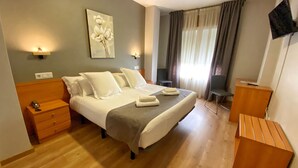 A hotel room with a bed, bedside tables, a desk, a chair, a TV, and a painting on the wall. - Hotel Ribeira Sacra (Monforte de Lemos)
