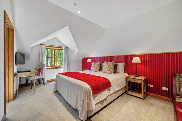 A bedroom with a bed, a desk, a chair, a lamp, and a window with curtains.