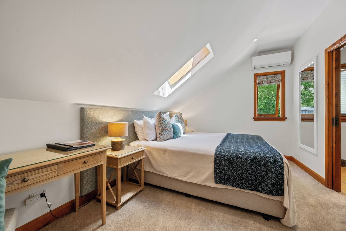 A bedroom with a bed, desk, and a window with a view.