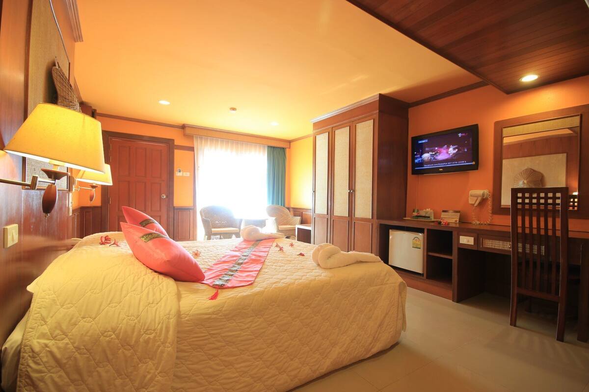 A hotel room with a bed, a desk, a television, and a chair.