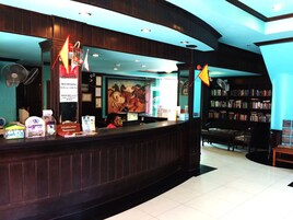 A reception desk with a computer, informational brochures, and a painting of horses. There are chairs and a bookshelf in the background.