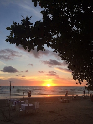 Na praia, areia branca, espreguiçadeiras, guarda-sóis