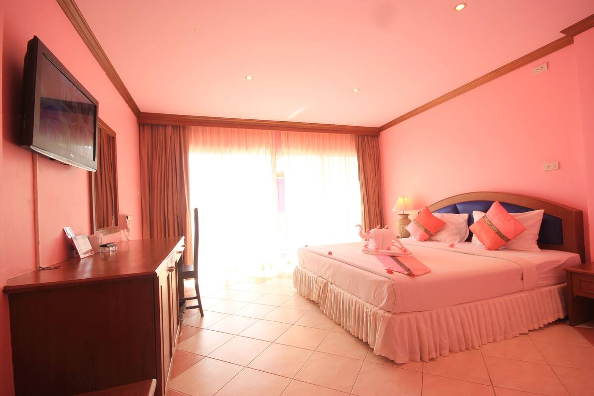 A hotel room with a bed, a desk, a television, and a window with curtains.