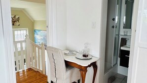 Un comedor con mesa de madera, una silla y una mesita con un decantador y copas. A la derecha hay un armario blanco y un acceso a otra habitación.