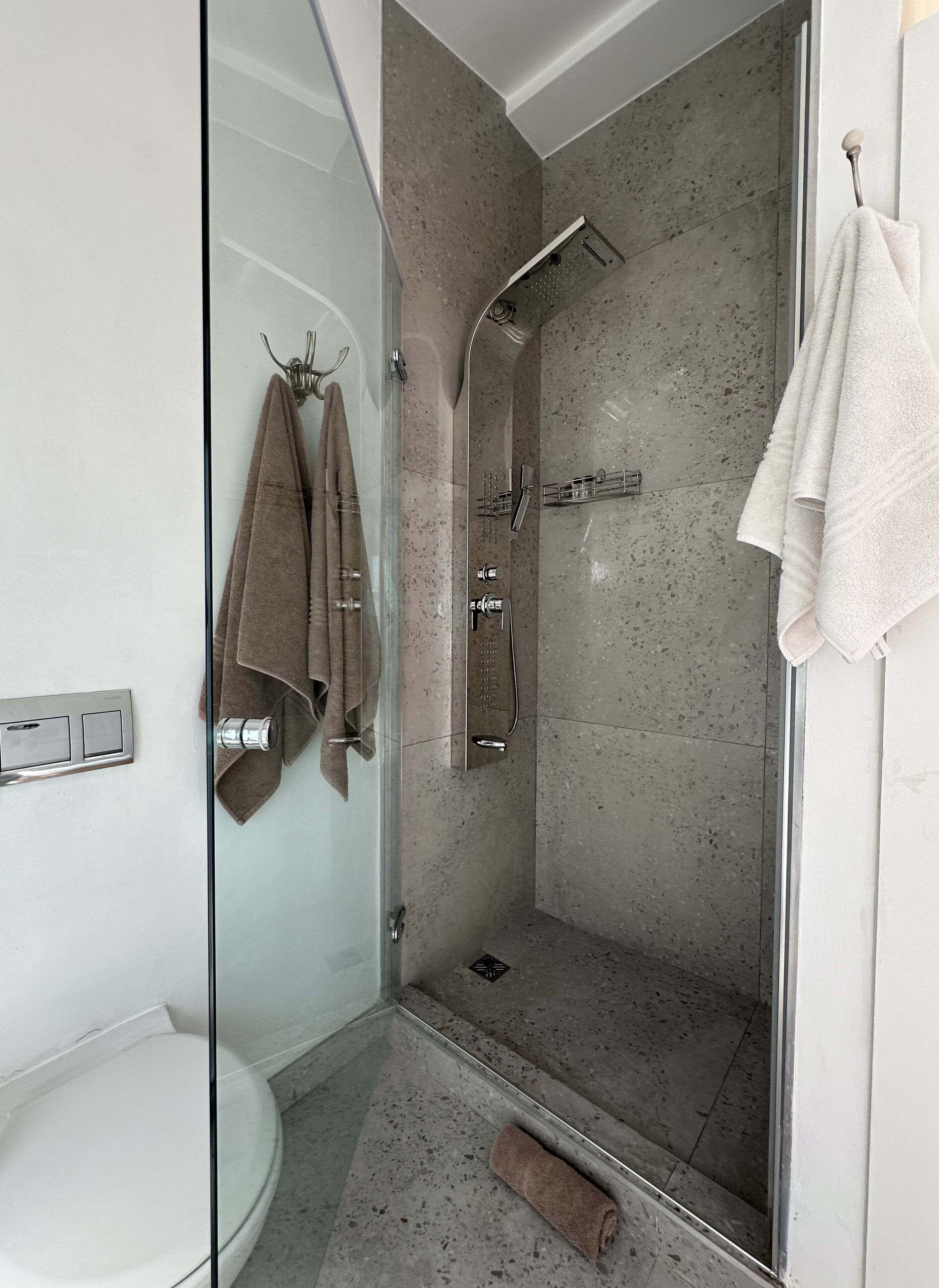 Un baño moderno con ducha de vidrio, inodoro y toallero.