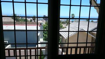 A view through a window with a grid pattern, overlooking a coastal area with buildings and a clear sky.