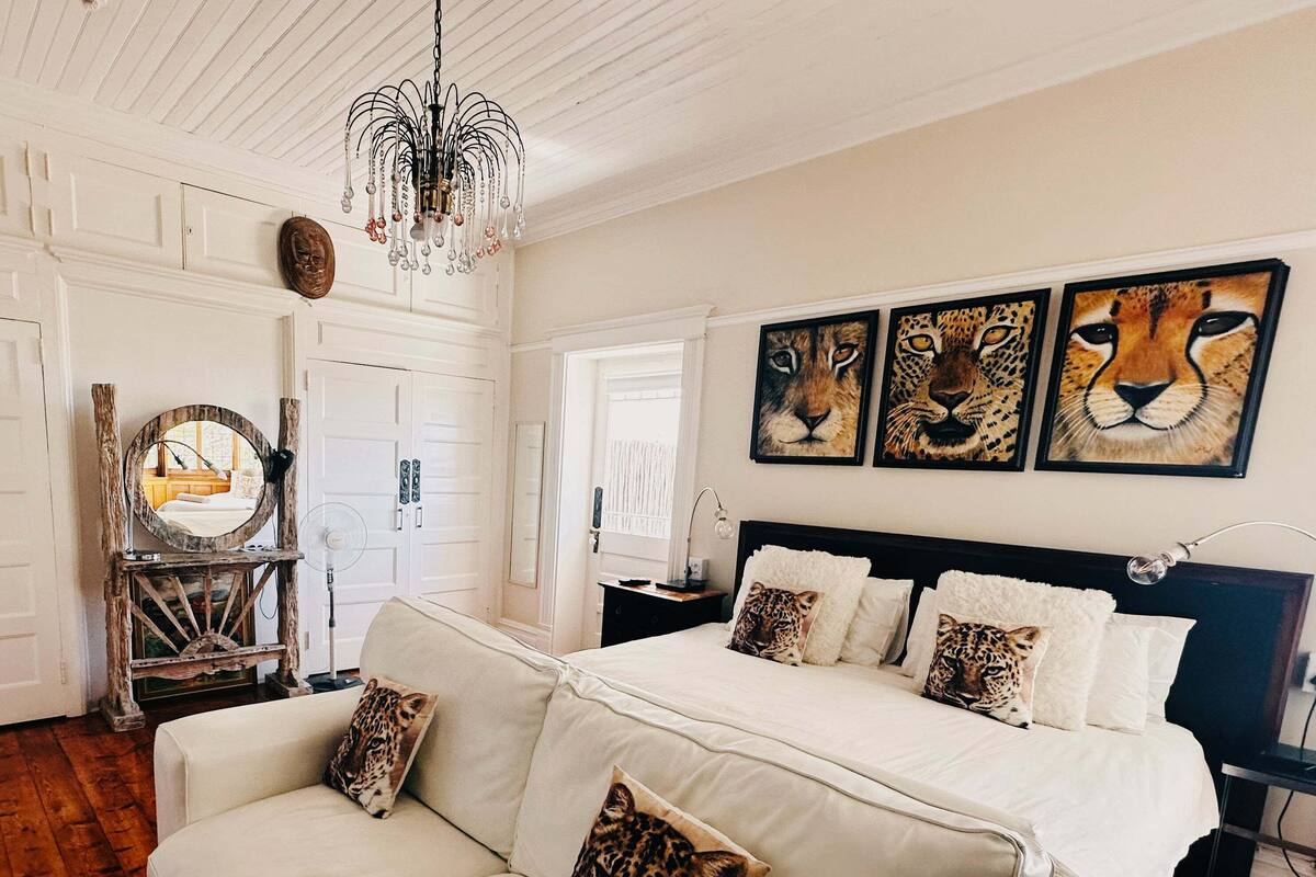 A bedroom with a large bed, a sofa, and leopard-themed pillows.