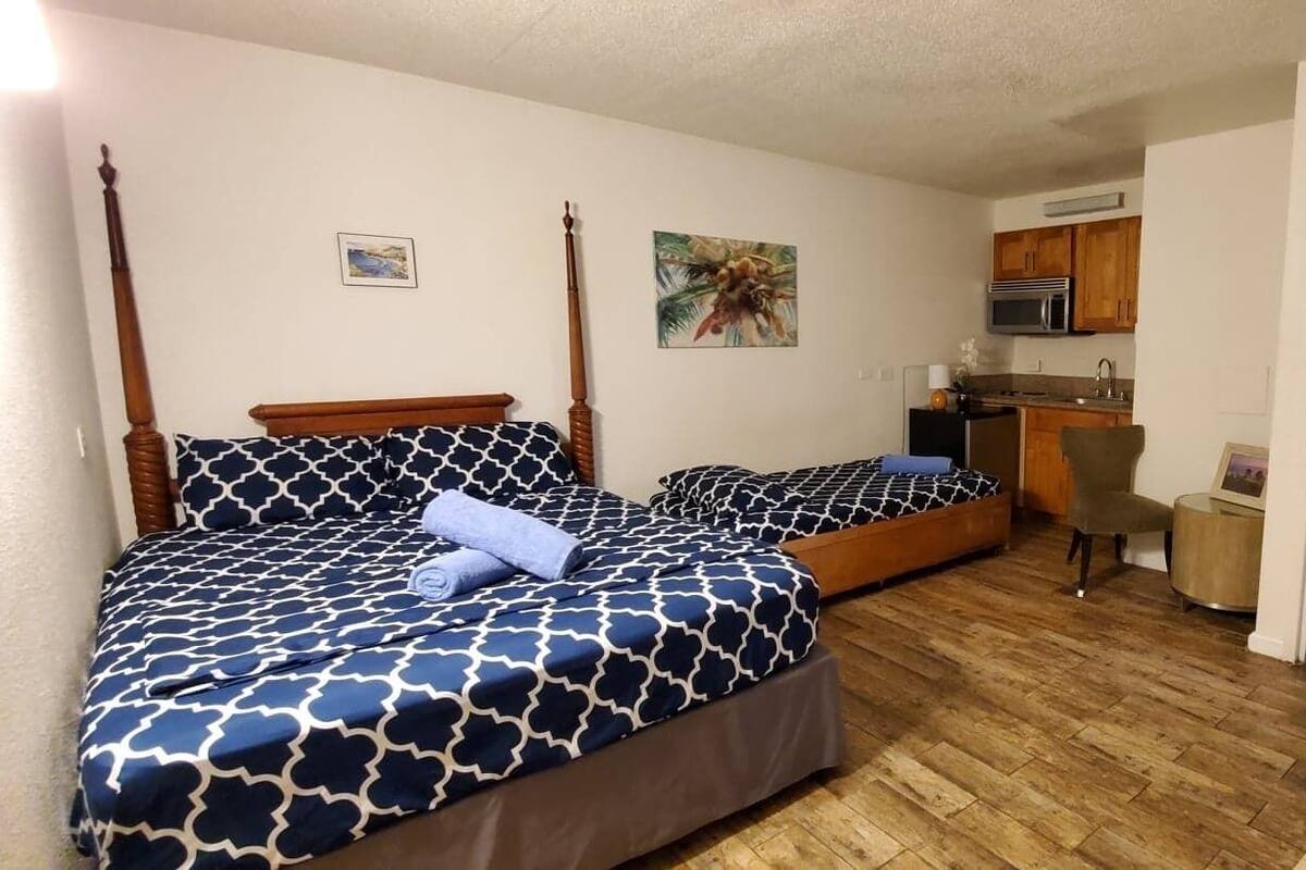 Ein Schlafzimmer mit zwei Betten, einem Schreibtisch, einem Stuhl, einer Mikrowelle und einem durchgegangenes Badezimmer.