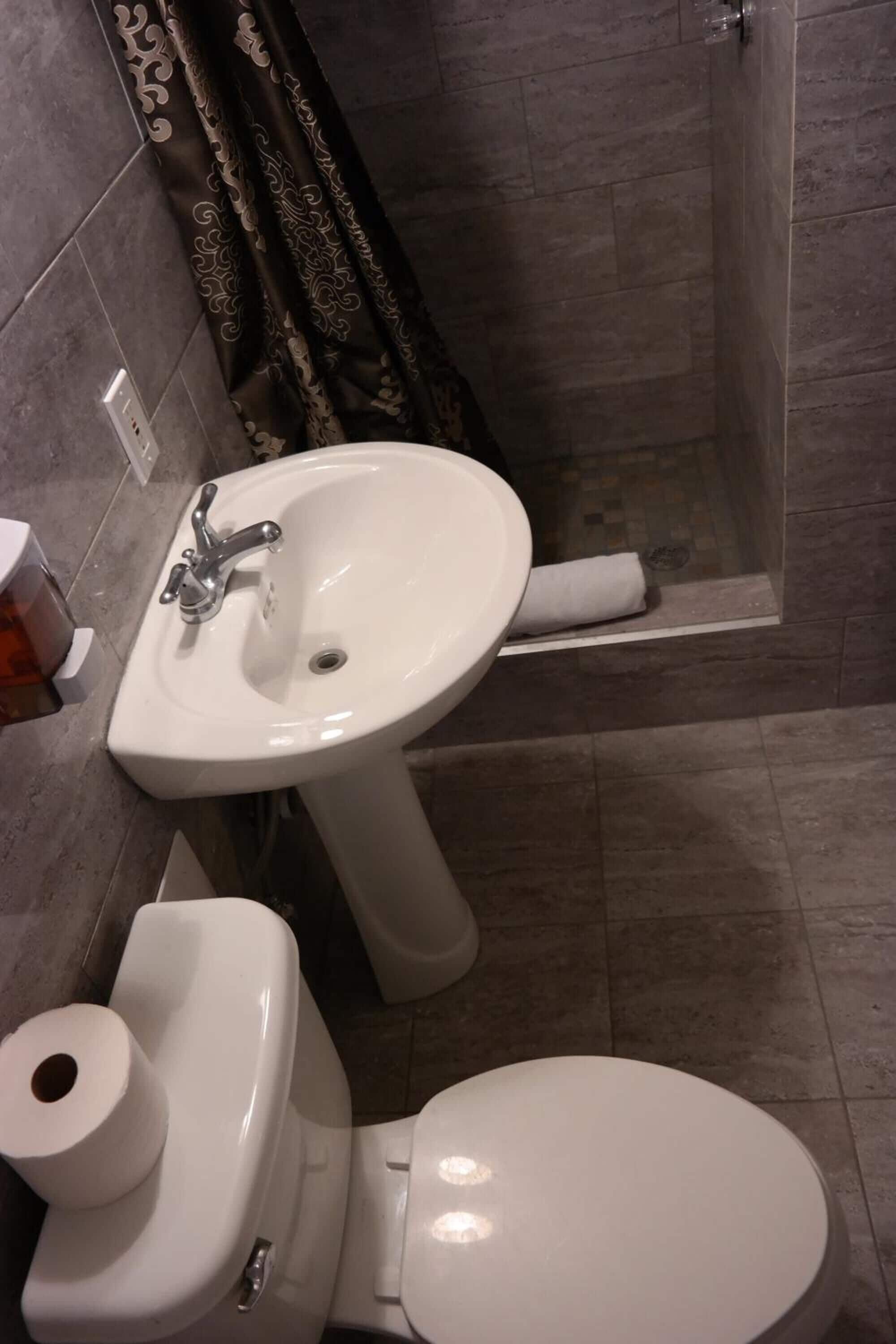 Casa de banho com lavatório branco, sanita e chuveiro.